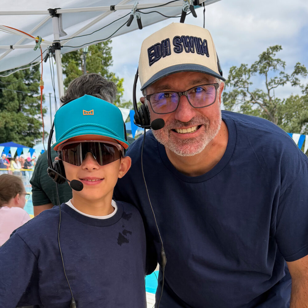 Ben Glickman and a young swimmer, both wearing announcer headsets, at an El Dorado Hills swim meet